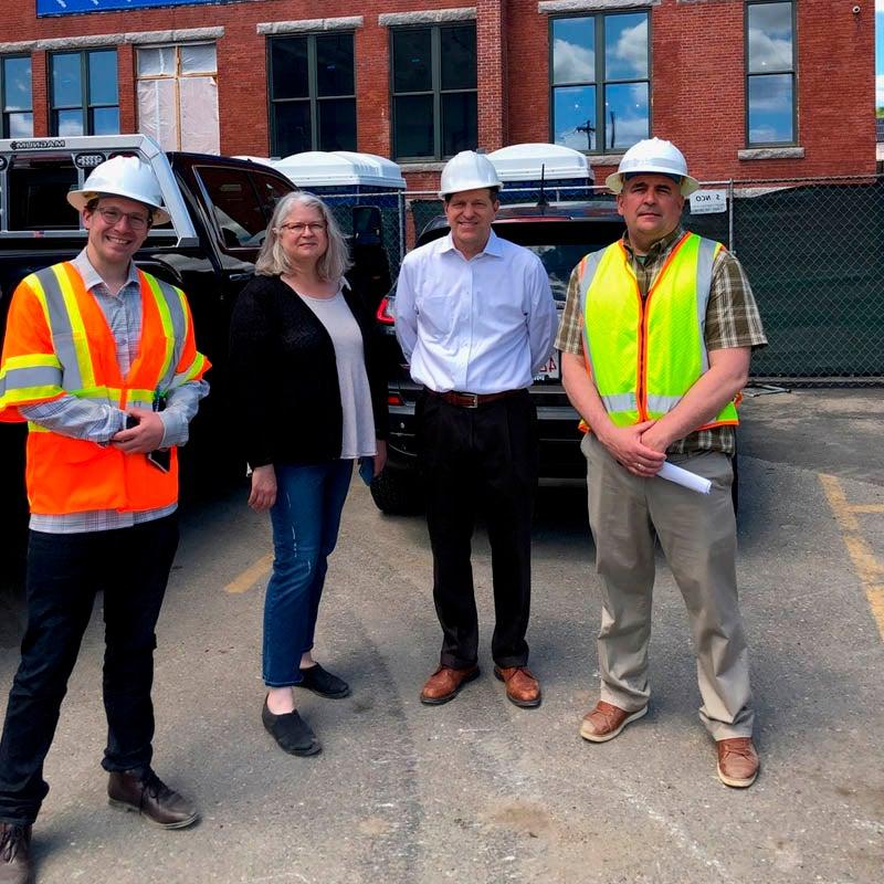 workers pose on street in front of Moran Square building construction