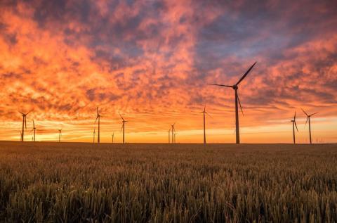 风 turbines in a flat field against a vibrant sunset